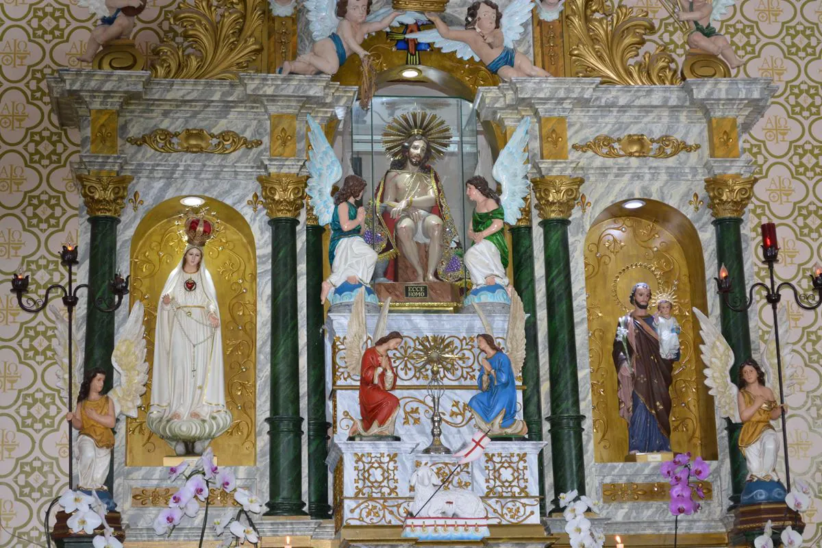 Altar-mor do Santuário, com a imagem do Senhor Bom Jesus ao centro, ladeada por imagens de santos e arranjos de flores.
